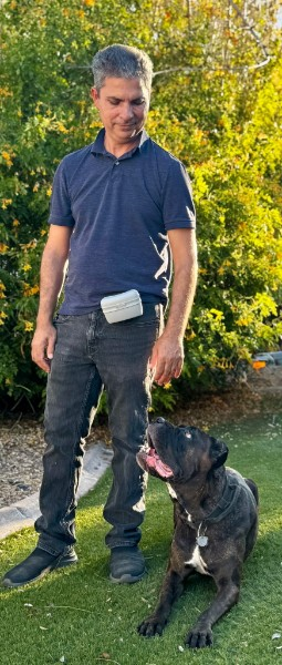 Win standing on the grass while a large dark dog looks up toward him